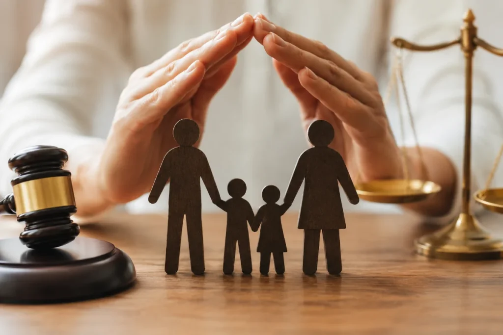 New Jersey parental rights: hands forming a protective roof over wooden family figures on a desk with a judge's gavel and scales of justice.